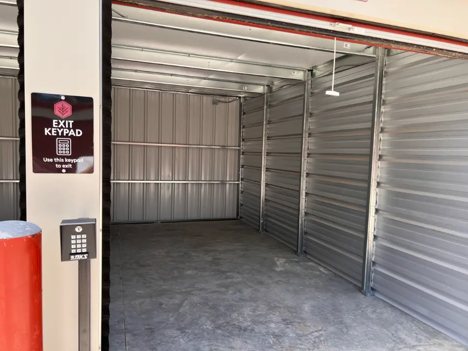 Open storage unit next to a security keypad at Cedar Storage